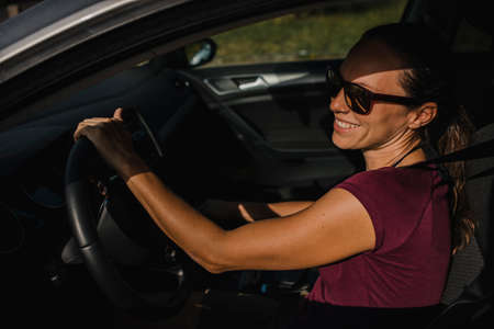 Woman in her car holding the steering wheel and smiling.の写真素材