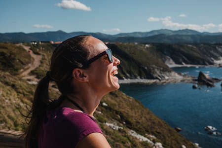 White woman laughing while look at the ocean in a coastal cliff.の写真素材