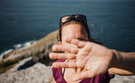 Playful woman trying to hide from photographer camera to avoid pics.の写真素材
