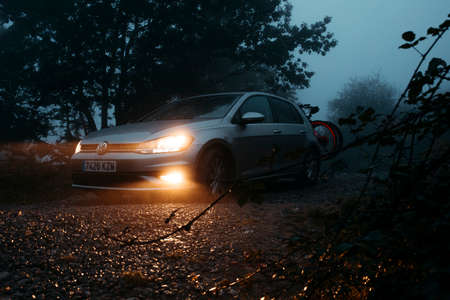 Asturias, Spain - September 9th 2020: A Volkswagen Golf VII with lights on being driven by a mountain path, with misty light, and entering into the forest, in Asturias mountain range, Spain.のeditorial素材