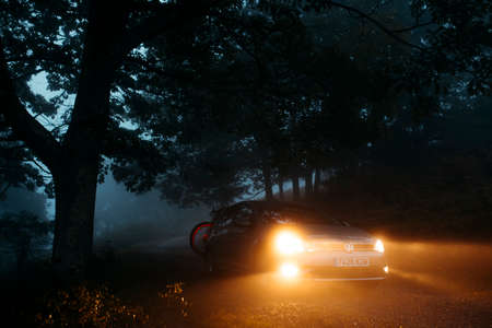 Asturias, Spain - September 9th 2020: A Volkswagen Golf VII with lights on being driven by a mountain path, with misty light, and entering into the forest, in Asturias mountain range, Spain.のeditorial素材