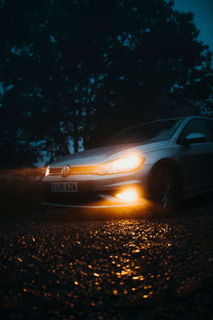 Asturias, Spain - September 9th 2020: A Volkswagen Golf VII with lights on being driven by a mountain path, with misty light, and entering into the forest, in Asturias mountain range, Spain.のeditorial素材