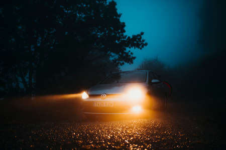 Asturias, Spain - September 9th 2020: A Volkswagen Golf VII with lights on being driven by a mountain path, with misty light, and entering into the forest, in Asturias mountain range, Spain.のeditorial素材