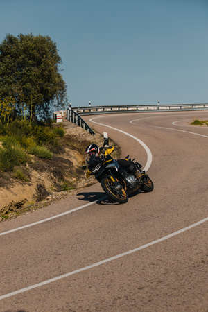 Almeria, Spain - May 5th 2021: Man riding a BMW 850 GS black and yellow motorcycle in a mountain road across beautiful turns, during Dunlop Xperience event in Almeria, Spain.のeditorial素材