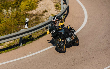 Almeria, Spain - May 5th 2021: Man riding a BMW 850 GS black and yellow motorcycle in a mountain road across beautiful turns, during Dunlop Xperience event in Almeria, Spain.のeditorial素材