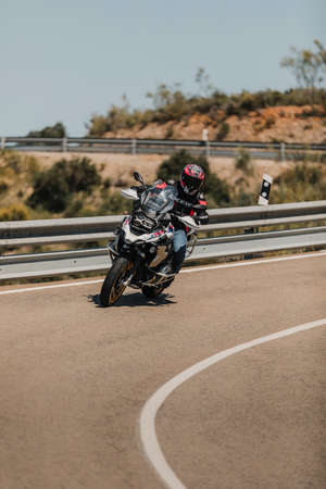 Almeria, Spain - May 5th 2021: Man riding a BMW R 1250 GS motorcycle in a mountain road across beautiful turns, during Dunlop Xperience event in Almeria, Spain.のeditorial素材