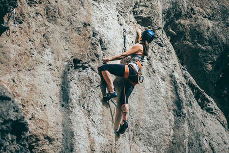 Woman climbing a rock with extreme effort in a vertical rock wallの写真素材