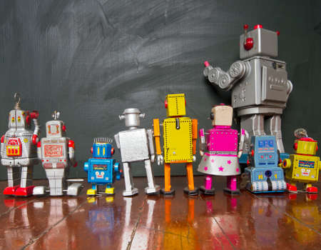 A  line of robot toys looking at a blackboardの写真素材