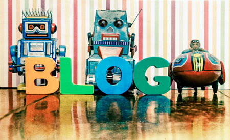 the word BLOG with wooden letters an a retro  robots & rocket toy on a wooden floor with reflection