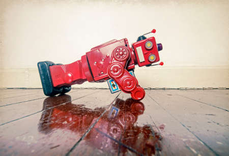red retro robot toy doing push ups on an old wooden floor with reflectionの写真素材