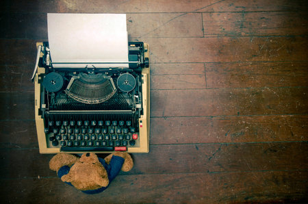 old teddy bear at a retro  typewriter  a wooden floor from above 