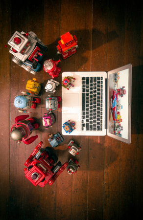 lots of  vintage robots watch a film on a laptop shot from above on a old wooden floor 