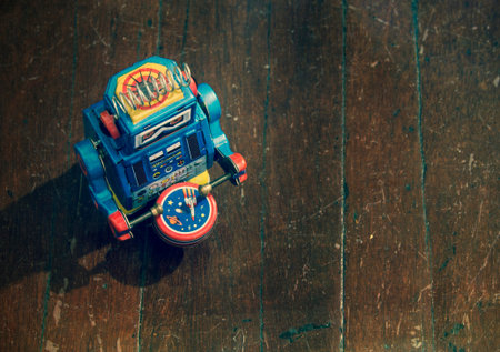 little blue robot drummer on old wooden floor from above 