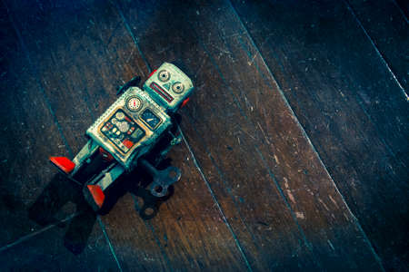sad beat up old retro robot on a wooden floor shot from above の写真素材
