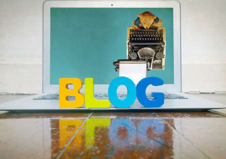 concept blogging with wooden letters on a laptop on a wooden floor  with reflection の写真素材