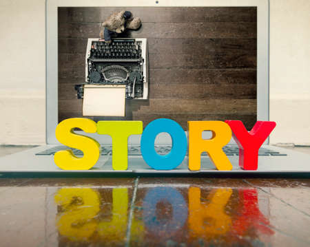 the word STORY  on a computer on a woodwn floor の写真素材
