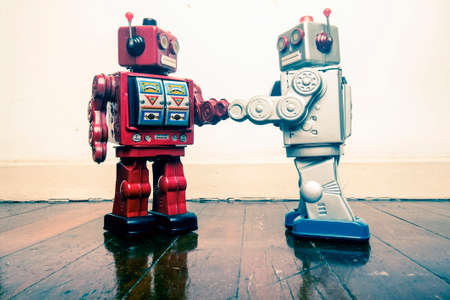 two vintage robot shake hands on a old wooden floor  toned imageの写真素材