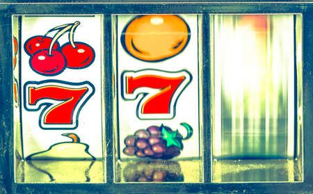 retro slot machine about to win 77 and spinning wheel macroの写真素材