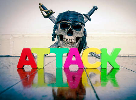 Skull and crossbones with the word ATTACK on a old wooden floor with reflectionの写真素材