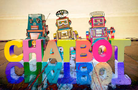 the word  CHAT BOT with wooden letters and retro toy robots  on an old wooden floor with reflectionの写真素材