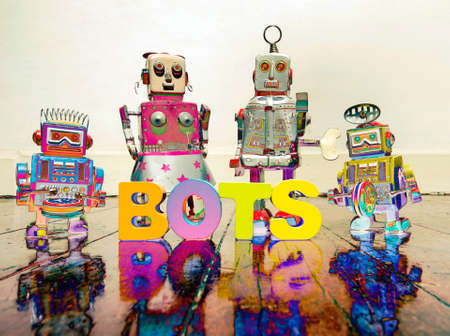 four retro robot toys and the word BOTS on a wooden floorの写真素材