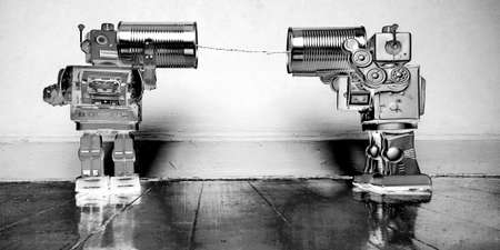 tow retro robots talk on tin can phones on an old wooden floor with reflectionの写真素材