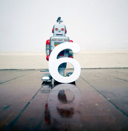 number  6 robot toy on a woden floor with reflection