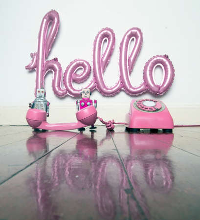 a  pink hello balloon and two  robots on the phone  with reflection  toned imageの写真素材