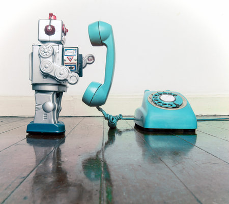big silver robot toy on  a blue  phone standing on an old wooden floor toned imageの写真素材