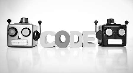 two retro robot head on white with the word CODE with wooden lettersの写真素材