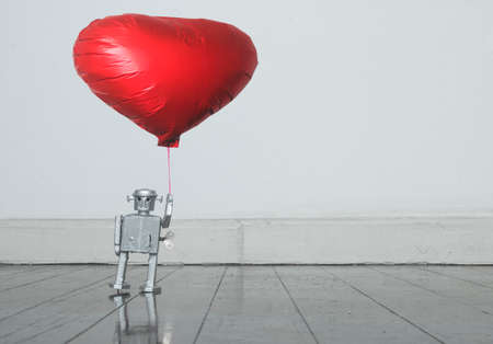 silver  robot holding red balloon standing on old wooden floor  copy spaceの写真素材