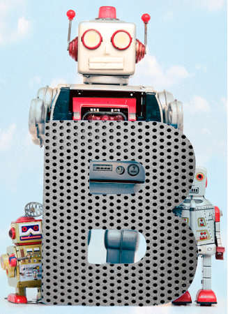 retro robots holding a big  metal letter B with blue sky and cloudsの写真素材