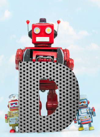 retro robots holding a big  metal letter D with blue sky and cloudsの写真素材