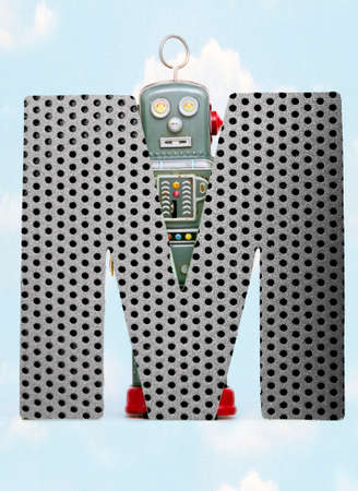 retro robots holding a big  metal letter  M with blue sky and cloudsの写真素材