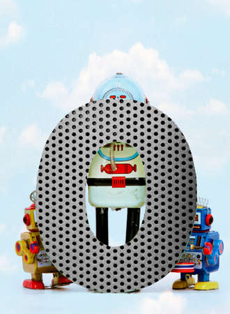 retro robots holding a big  metal letter O  with blue sky and cloudsの写真素材