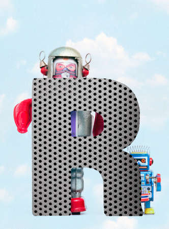 retro robots holding a big  metal letter  R with blue sky and cloudsの写真素材