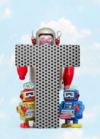 retro robots holding a big  metal letter  T with blue sky and cloudsの写真素材