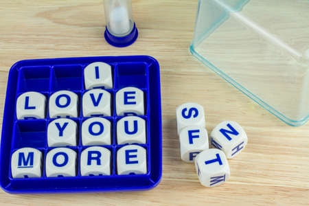 Wording Game I LOVE YOU MORE in Blue Tray on Wooden Board with Sand Timer and Clear Tray Coverの写真素材