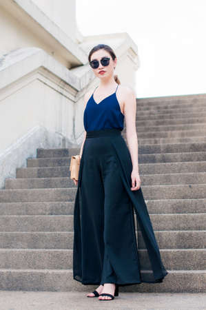 Confident Young Asian Working Woman with Sunglasses Posting in a Urban Concrete Stairwayの写真素材
