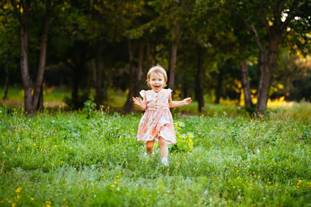 Happy cute little girl running on the grass in the park. Happinessの写真素材