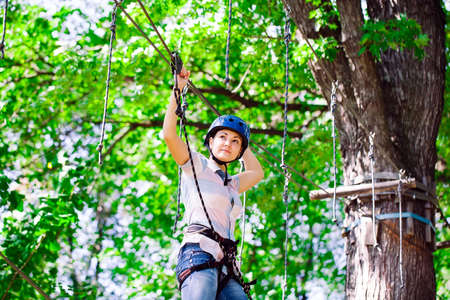 adventure climbing high wire park - people on course in mountain helmet and safety equipmentの写真素材