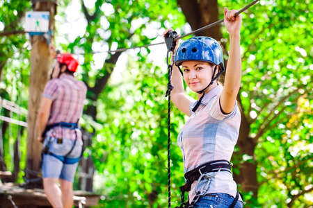 adventure climbing high wire park - people on course in mountain helmet and safety equipmentの写真素材
