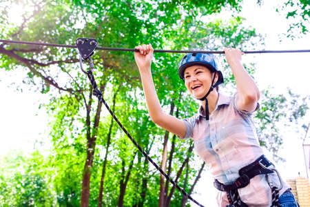 adventure climbing high wire park - people on course in mountain helmet and safety equipmentの写真素材