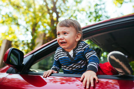 Crying baby boy in car. The boy is crying and wants to get out of the manicheの写真素材