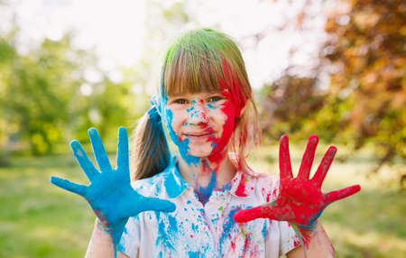 Portrait of a cute girl painted in the colors of Holi festivalの写真素材