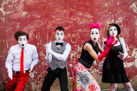 Four armed mimes standing on a red wall.の写真素材