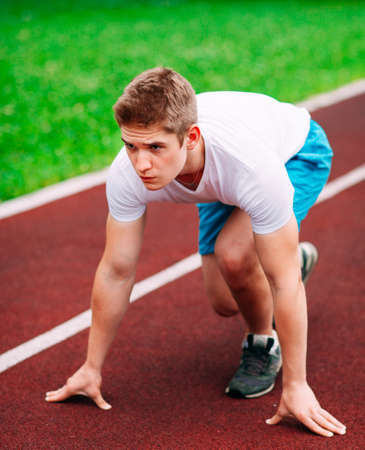 Athletic man on track starting to run. Healthy fitness concept with active lifestyle.の写真素材