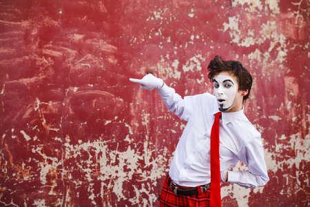 Mime points a finger at the center against a background of a red wallの写真素材