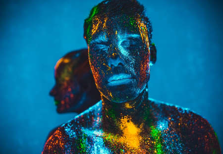 people are colored fluorescent powder. a pair of lovers dancing at a discoの写真素材