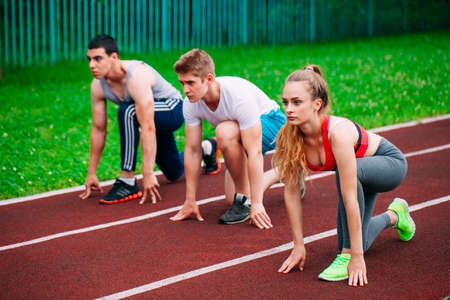 Athletic young people on track starting to run. Healthy fitness concept with active lifestyle.の写真素材